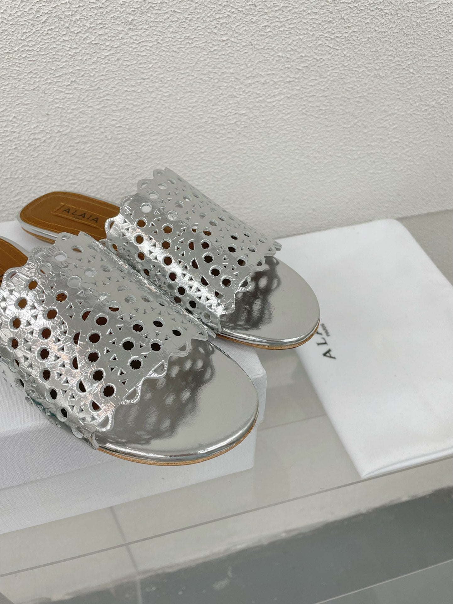 ALAIA VIENNE FLAT MULES IN SILVER LAMBSKIN